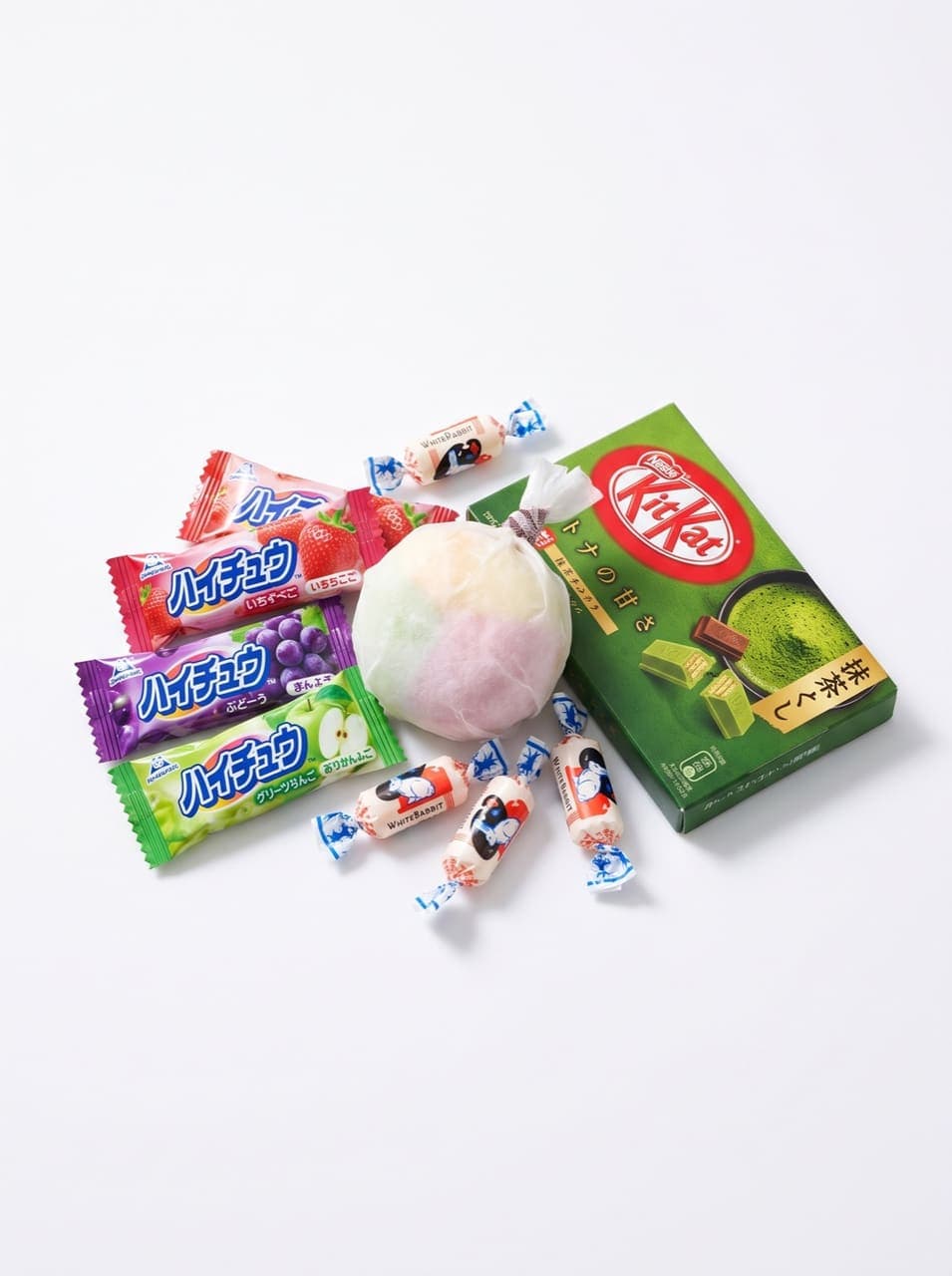 Japanese sweets: Hi-Chew packs, White Rabbit candy, wrapped mochi, and a matcha KitKat box on a white studio background